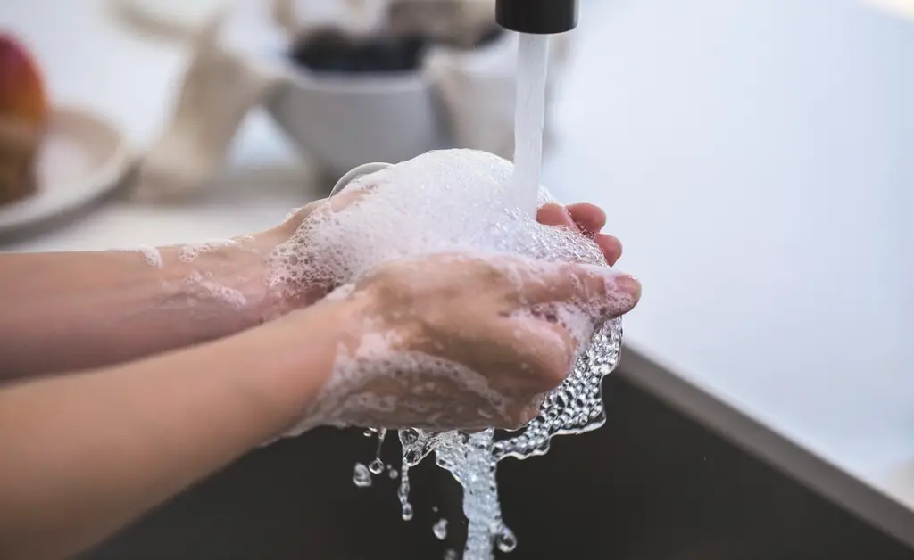 Bọt rửa dưới vòi nước trên bàn tay
